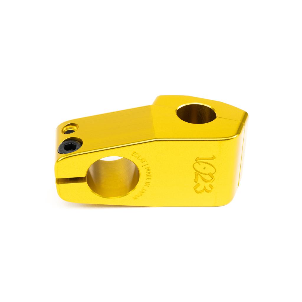 The Eclat 1023 Stem is a gold anodized, CNC machined clamp with two circular openings, a small hex screw, and is engraved with "1023" and "MADE IN JAPAN.