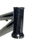 Close-up of the S&M Big Jumper V2 26 Inch Dirt Jumper Frame's black head tube, featuring an embossed shield logo with “S” and “M”; designed for a suspension fork and disc brake.