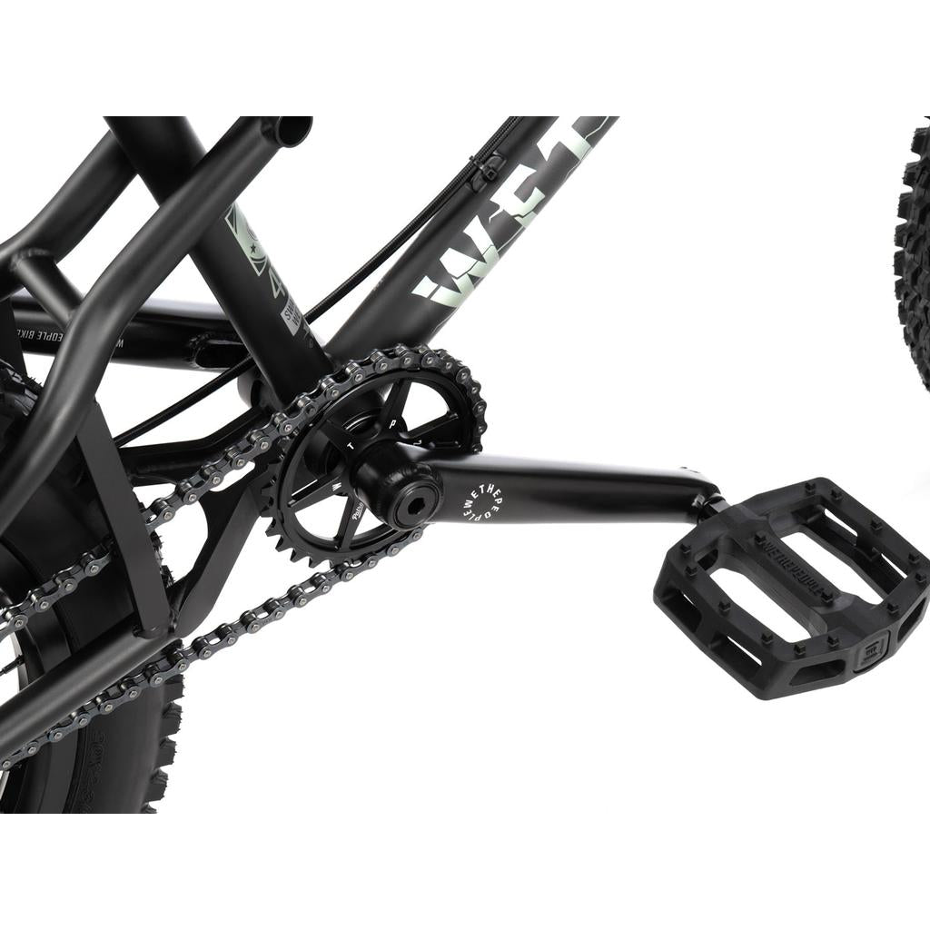 Close-up of a black downhill drivetrain on a Wethepeople Swampmaster 20 Inch Bike (Rock Shox Shock), showing the crank, sprocket, chain, and pedal.