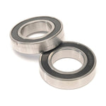 The Eclat Shift Hub Bearing Set includes two metal bearings with black rubber seals, shown positioned flat and diagonally—perfect replacements for your Eclat Shift Hub.