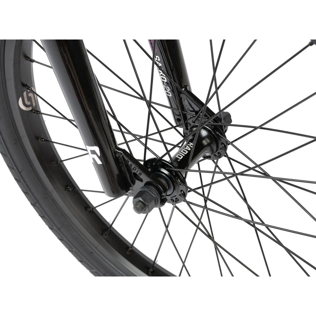 Close-up of the Radio Saiko 20 Inch Bike front wheel, highlighting black spokes, axle, Salt Tracer Tyres, and part of the fork with visible brand markings.