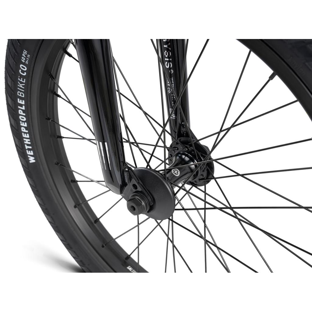 Close-up of the black front wheel on the Wethepeople Crysis 20 Inch BMX Bike, showcasing SaltPlus spokes, fork, and hub. The sidewall displays "Wethepeople Bike Co." for a sleek Crysis Bike look.