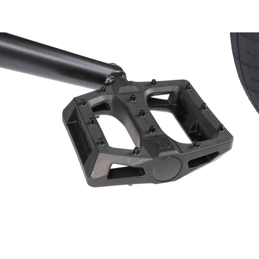 Black BMX bicycle pedal with textured grip and plastic pins attached to a crank arm on a Wethepeople Arcade 20 Inch Bike.