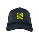 The S&M Rambler Sharpie Shield Cap is a black mesh-back hat with a yellow stylized shield and letter design on the front panel. It features an adjustable snapback closure for comfort, breathability, and a perfect fit.