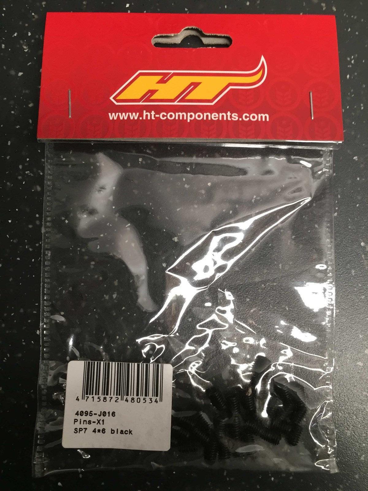 A plastic bag labeled "HT Components Pedal Pins - X1, X2, T1, D2" contains several black pedal pins with product code 4095-J016 (SP7 4x6), featuring a barcode and product label on the front.