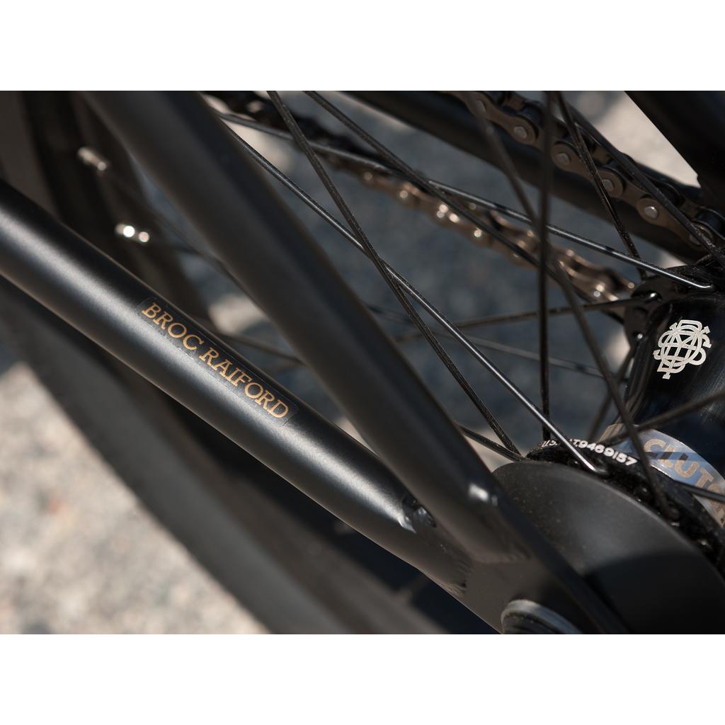 Close-up of a black Sunday Forecaster 20 Inch Bike (2025) / Broc Raiford with "BROC RAIFORD" on the 100% chromoly frame and visible wheel spokes.