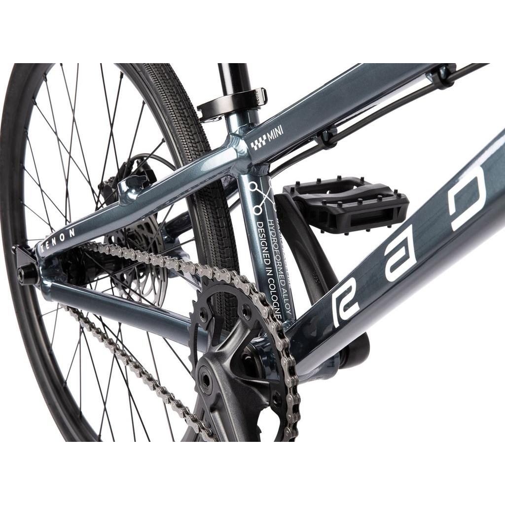 Close-up of a Radio Xenon Mini Disc 20 Inch Bike, highlighting its hydroformed 6061-T6 alloy frame, chain, pedal, rear wheel, and metallic blue finish with white branding and design accents.