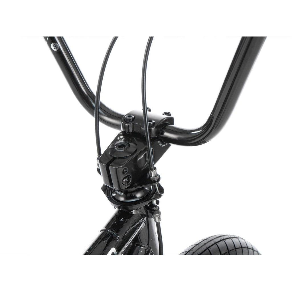 Close-up of the handlebar and front tire on the Radio Astron FS 20 Inch Bike, showcasing the stem, cables, and part of the front suspension fork on this black BMX bike with its full chromoly frame.