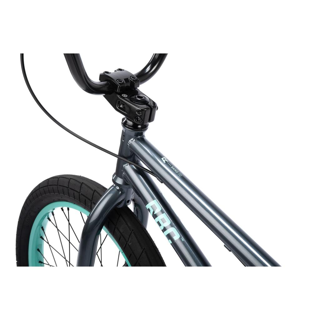 Close-up of the Radio Saiko 20 Inch Bike's front shows handlebars, stem, and front wheel with a teal rim and Salt Tracer Tyres, plus part of its metallic gray frame against a white background.