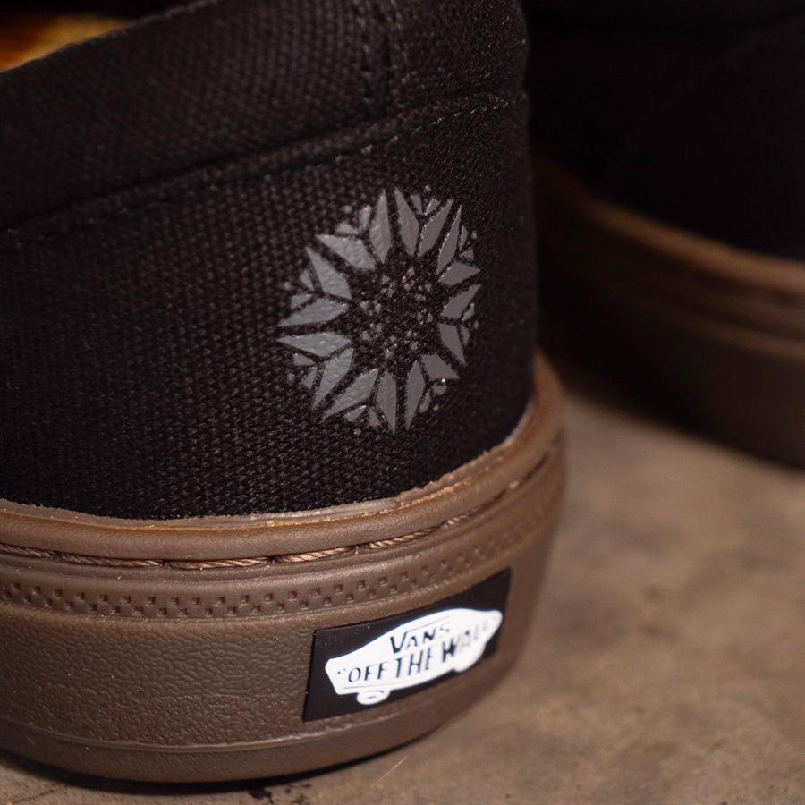 A pair of black Vans BMX Slip On Shoes (Dennis Enarson) with a flower on them.