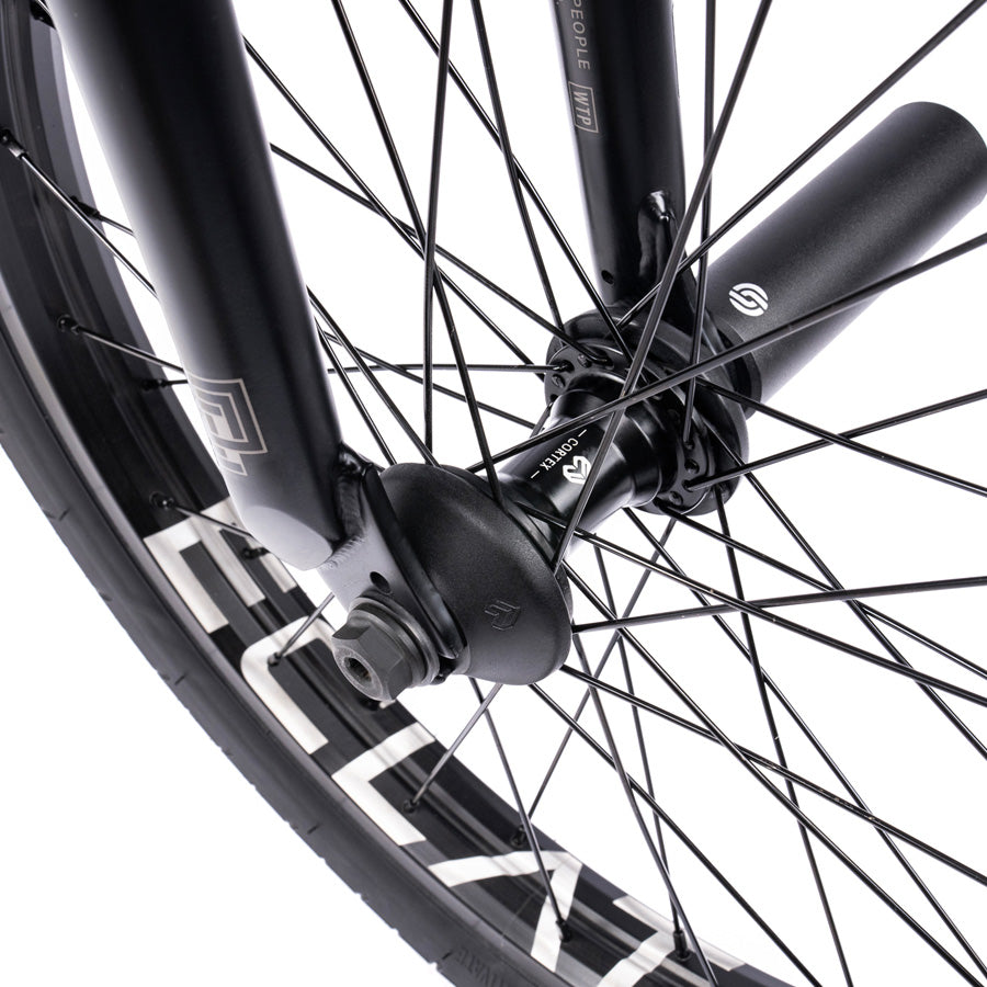 A close up of a black BMX wheel with white spokes on a Wethepeople Trust 20 Inch Freecoaster Bike.