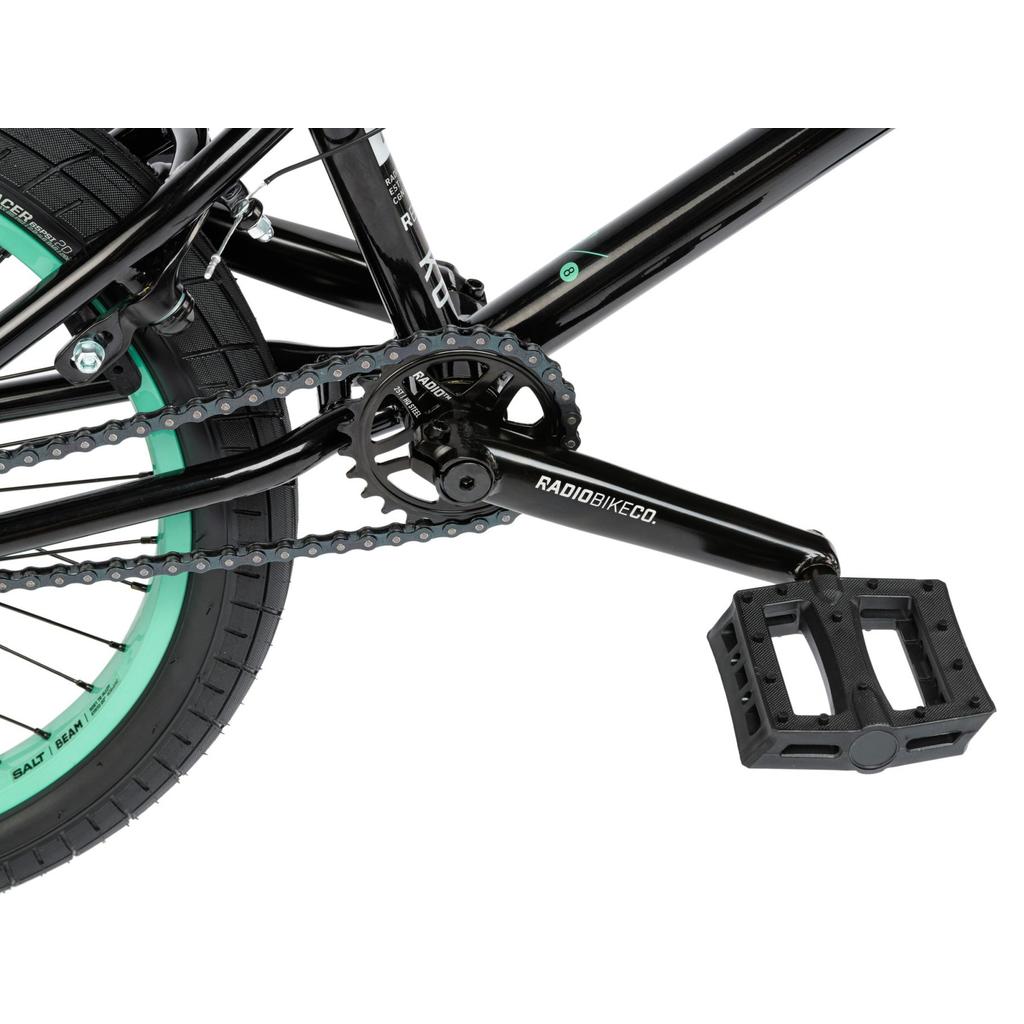 Close-up of the crankset, chainring, chain, and pedal on a black-framed Radio Saiko 20 Inch Bike with green-accented Salt Tracer Tyres.