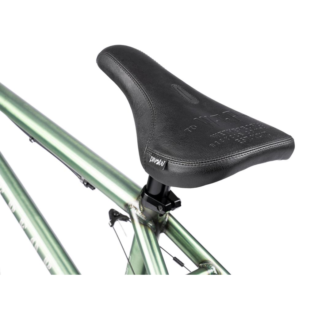 Close-up of a black bicycle seat on a metallic green frame, showing the saddle and seat post on the Wethepeople Revolver 20 Inch Bike, built with top aftermarket parts and a lifetime guarantee on the frame and fork.