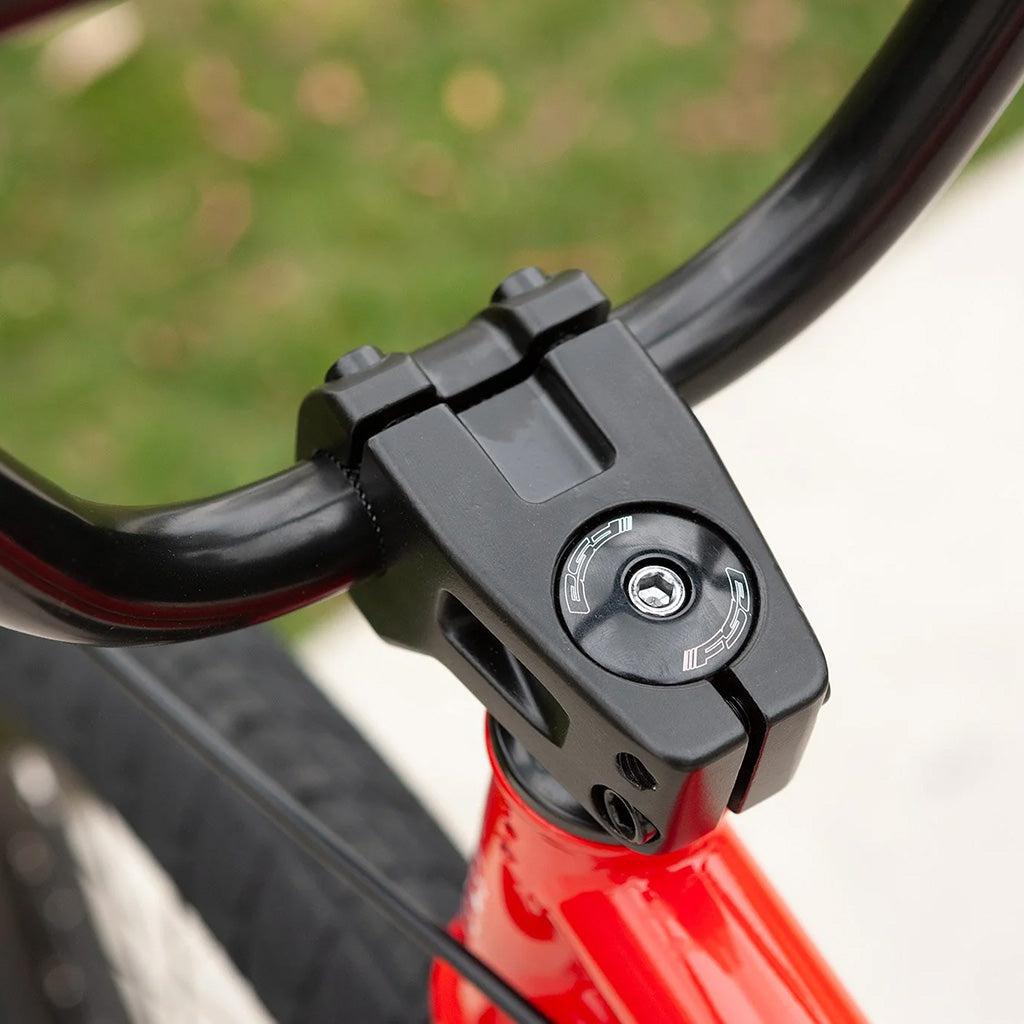 A close up of the handlebar on a red Sunday Blueprint 20 inch Bike.
