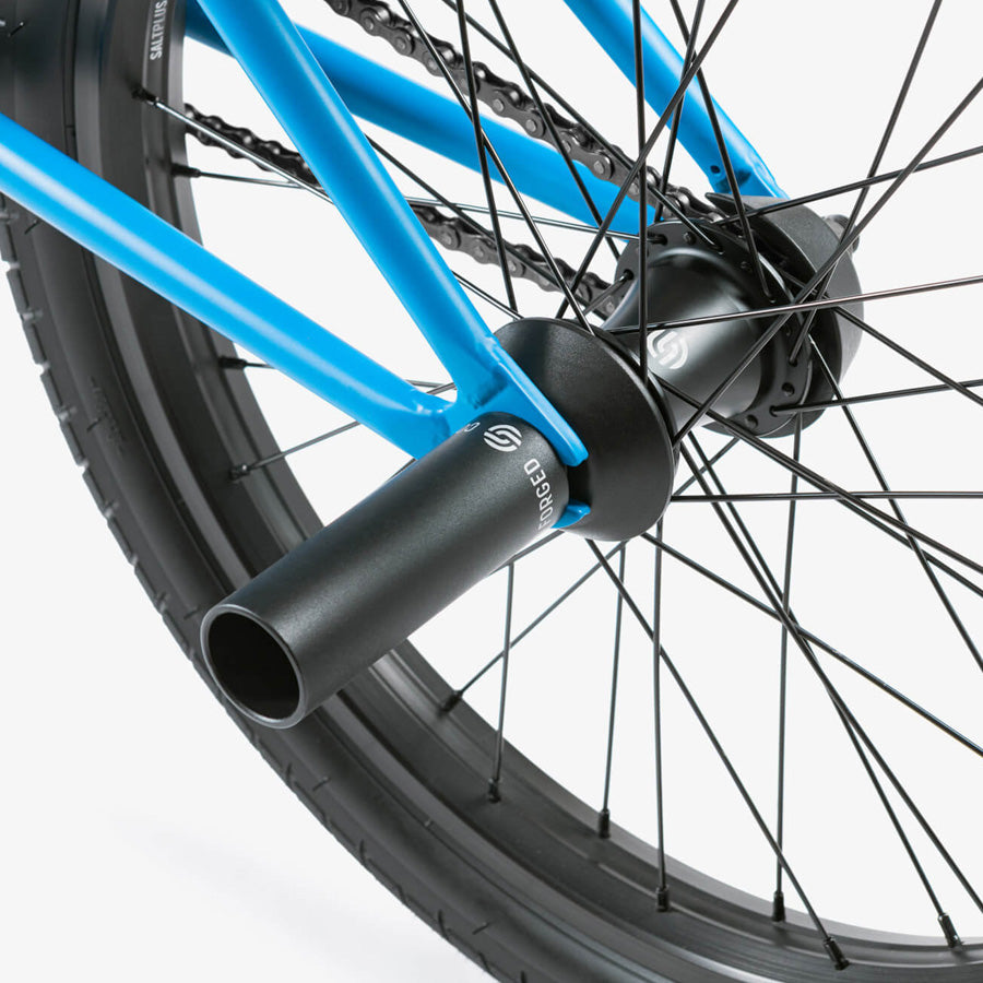 A close up of a blue bike wheel with black spokes on a Wethepeople Reason 20 Inch BMX Bike for urban warriors.