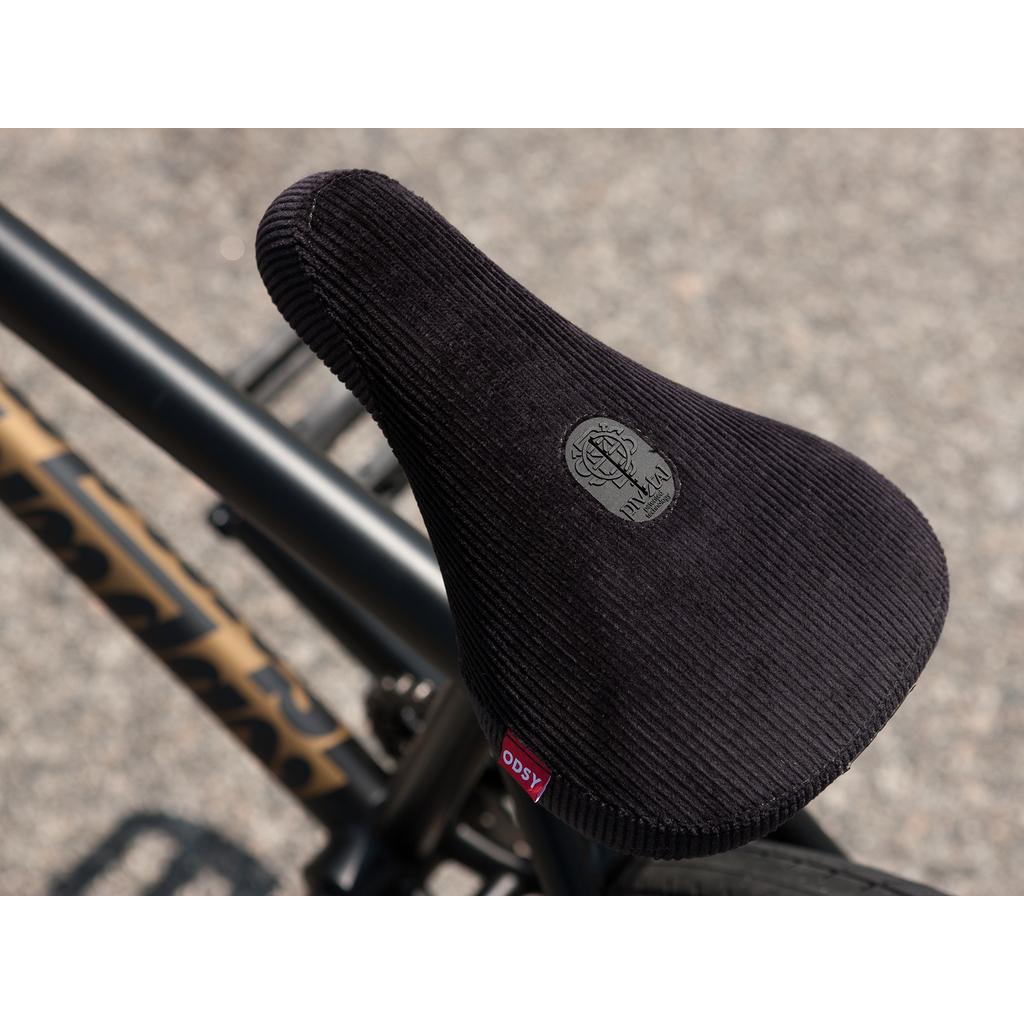 Close-up of a black textured bike seat with a logo and "Method" on top, attached to the Sunday Forecaster 20 Inch Bike (2025) / Broc Raiford, featuring a patterned frame design.
