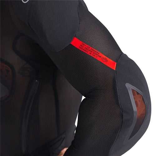 A close-up of a person's arm in the TLD 26.1 Stage Ghost D3O LS Protective Shirt Baselayer, featuring black mesh-textured fabric, a red label, reflective accents, and discreet D3O Ghost protection.
