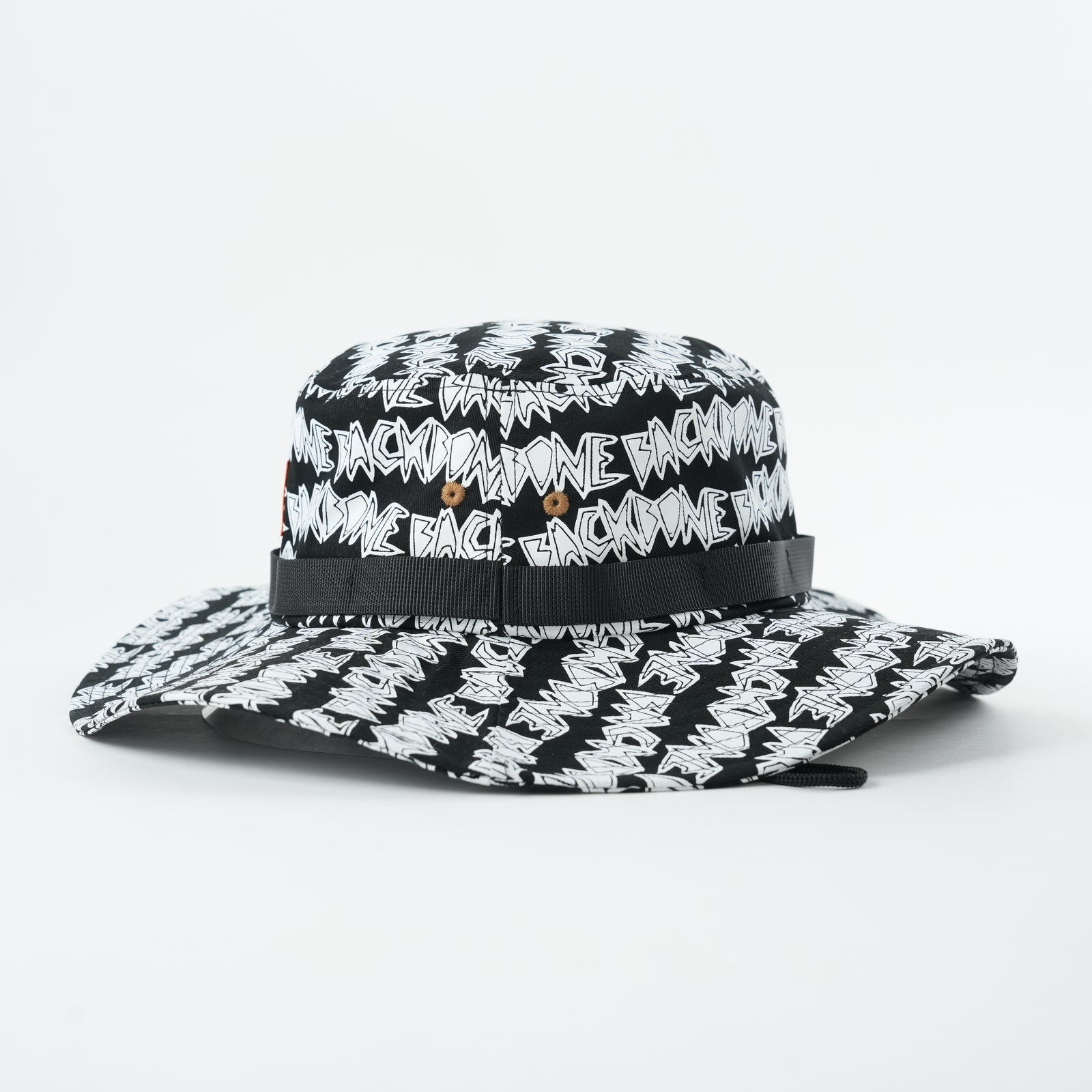 The Backbone AO Boonie is a black and white wide-brim hat with "BACK IN DA GAME" text pattern and metal eyelets on each side—ideal for expressing your Backbone BMX style.