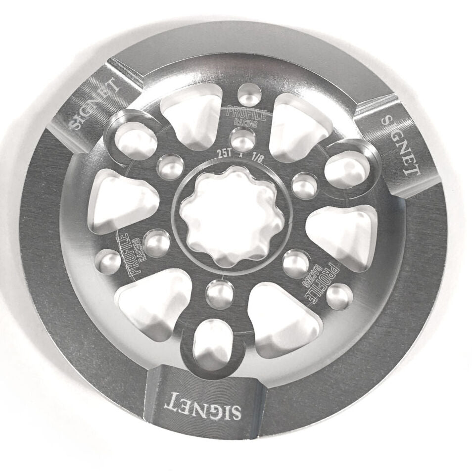 The PROFILE Signet Universal Sprocket W/ guard is shown in silver with "SIGNET" and "PROFILE RACING 25T 1/8" engraving, designed for wide BMX crank compatibility, displayed against a white background.