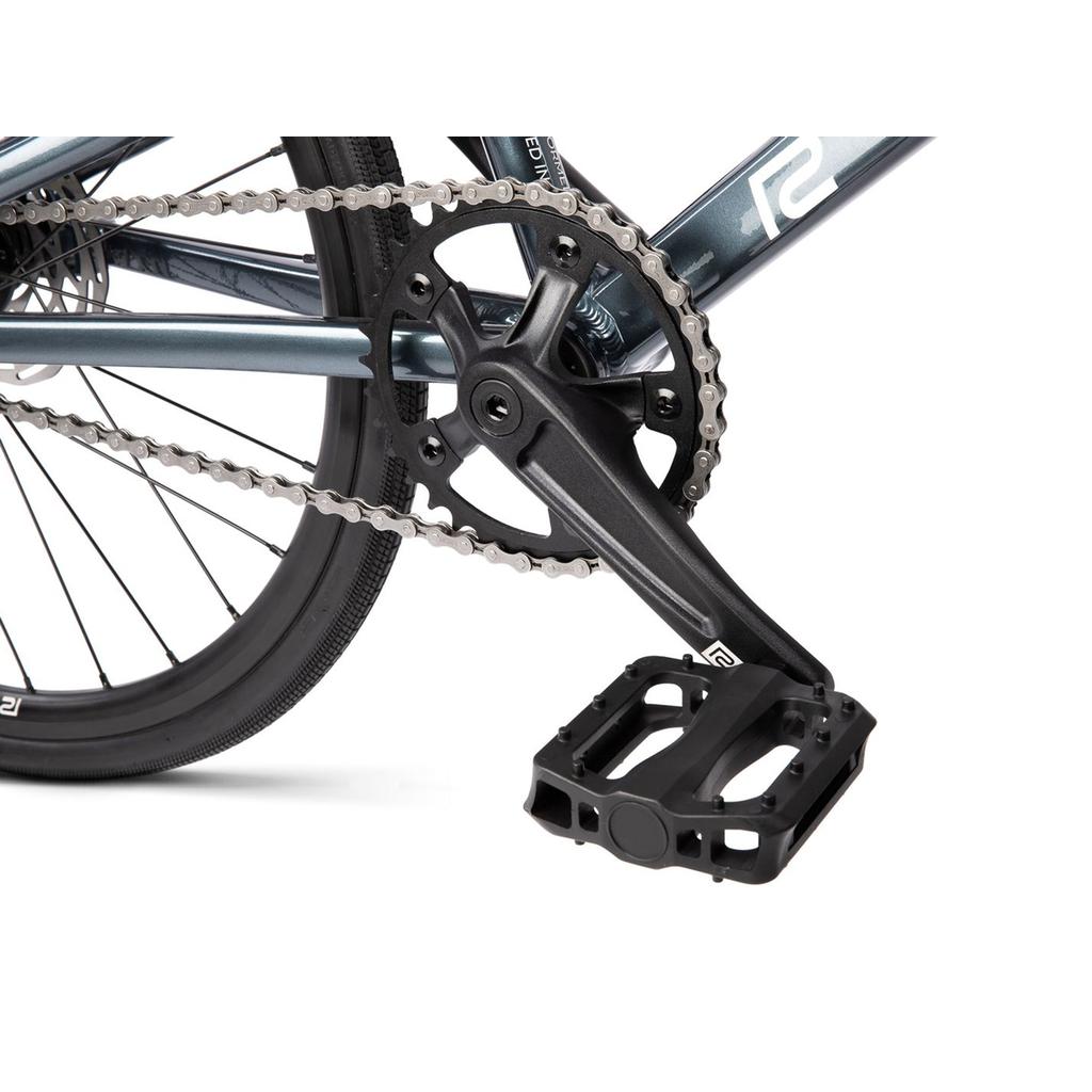 Close-up of the Radio Xenon Mini Disc 20 Inch Bike's lightweight BMX crankset, chainring, chain, pedal, and rear wheel with a hydroformed 6061-T6 alloy frame shown against a white background.