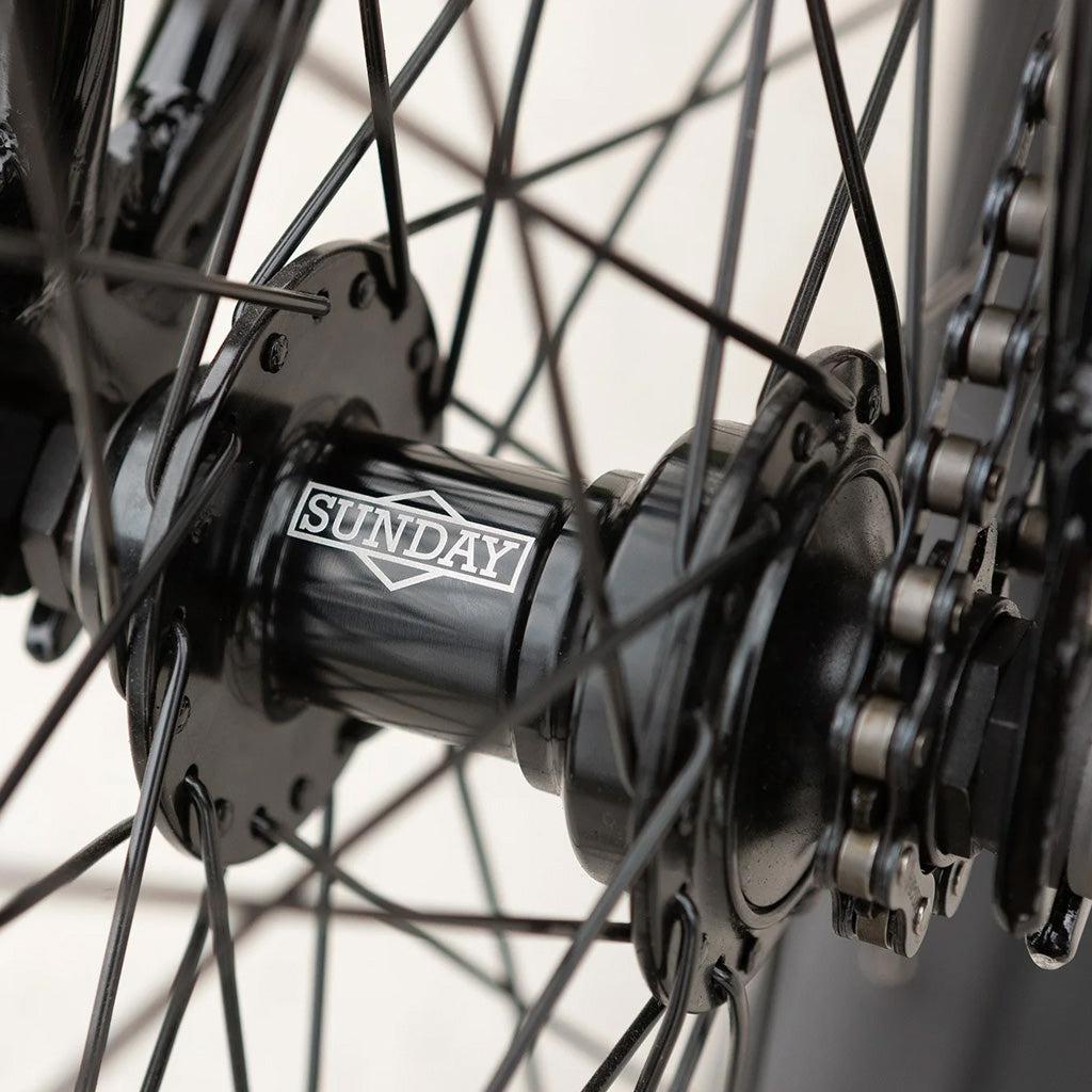 A close up of a blueprint-inspired Sunday Blueprint 20 inch Bike wheel with a chain and spokes.