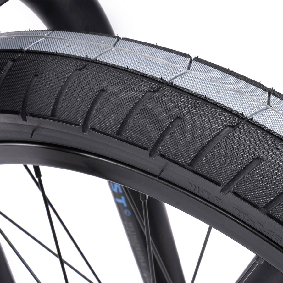 A close up view of a black bicycle tire featuring the Wethepeople Trust 20 Inch Cassette Bike with Hybrid Technology for ultimate performance.