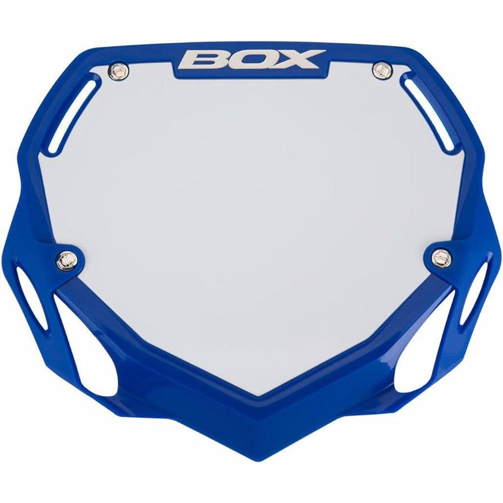 The Box Two Phase 1 Number Plate Large is a blue and white rectangular BMX number plate with the word "BOX" Component at the top, featuring cut-out corners and four attachment points, ideal for Phase 1 plate competitors.