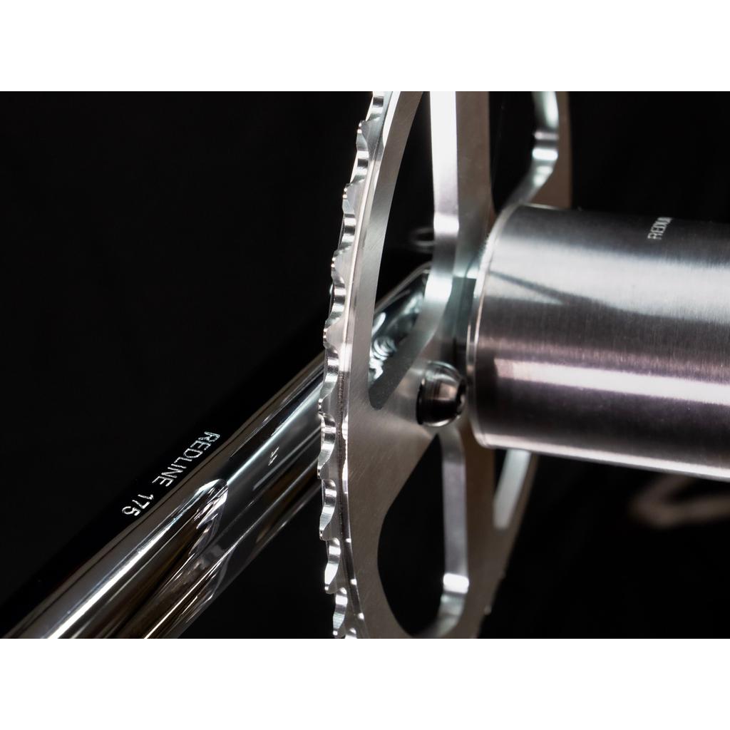 Close-up of a Redline Vintage Flight 401 Crank Set with a silver crank and chainring, featuring "REDLINE 175" on the polished arm, made from durable 4130 chromoly, shown against a black background.