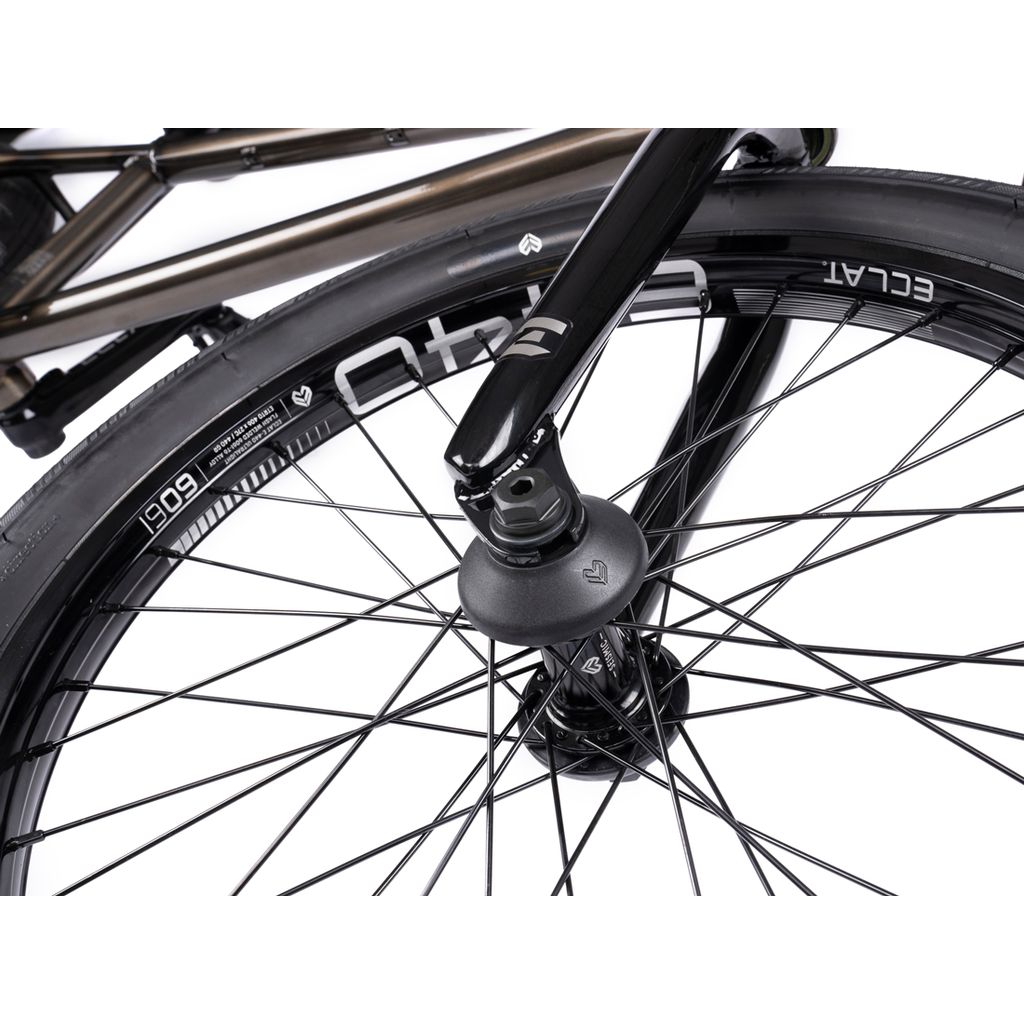 Close-up of a Wethepeople Envy 20 Inch Bike wheel reveals its detailed spokes, sleek black fork, and branded tire. This BMX marvel mirrors the precision seen in Eclat Tibia Cranks.