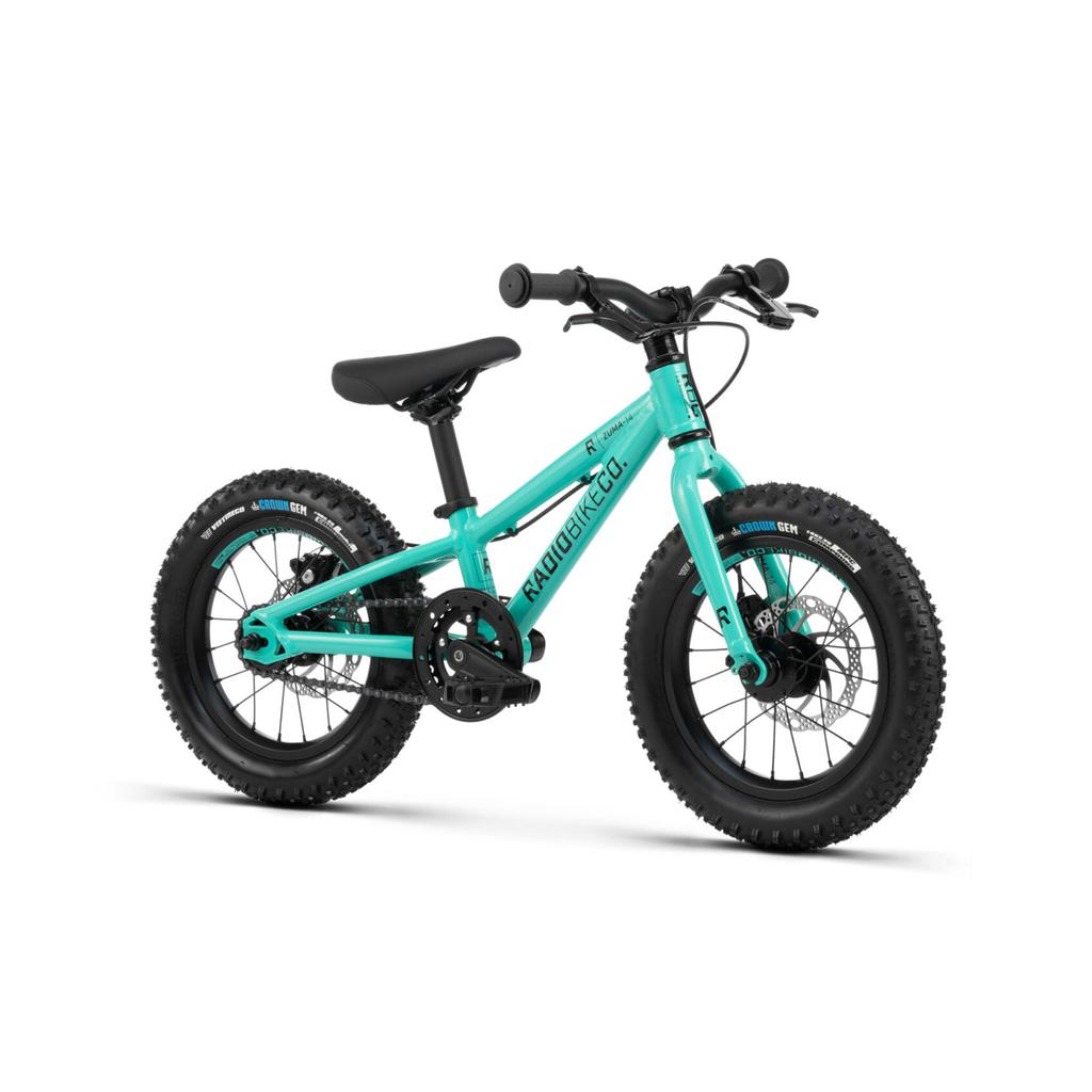 The Radio Zuma 14 Inch Bike, a turquoise kids’ mountain bike with thick black tires, a black seat, and straight handlebars, is displayed against a white background.