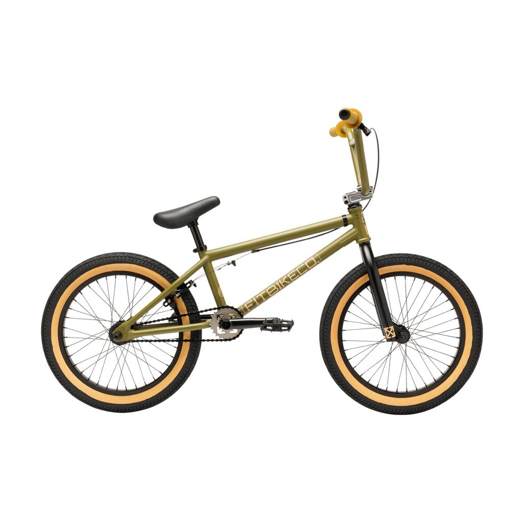 The Fit Bike Co Misfit 18 Inch Bike is displayed in green with a lightweight BMX frame, tan tires, black seat, and black pedals, shown in a side profile view against a white background.