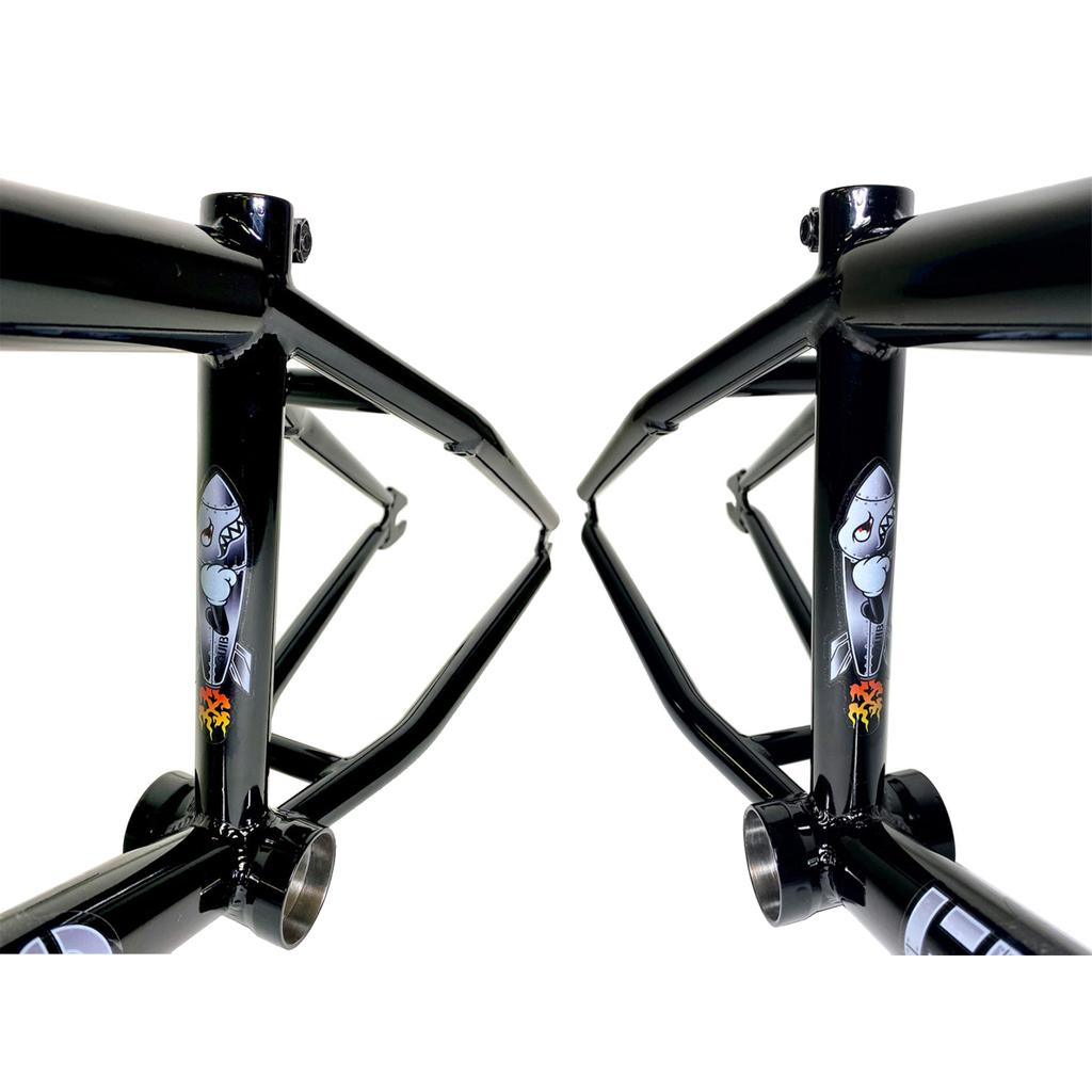 Two Fit Bike Co Squib 18 Inch BMX frames in black are side by side, each showcasing a cartoon shark with flames decal near the bottom bracket. Both frames are made from durable chromoly for lasting strength.