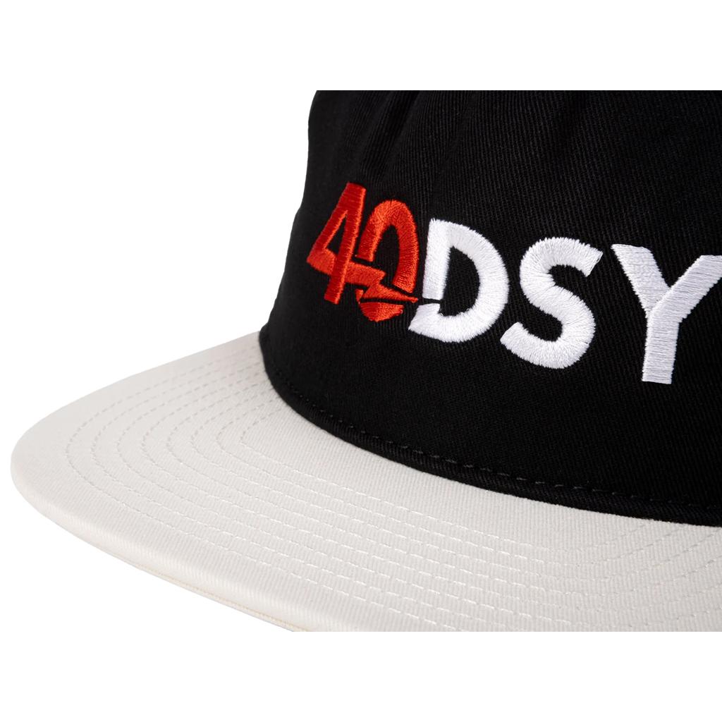 Close-up of the Odyssey 40DSY Cap from the holiday lineup, showcasing "40DSY" embroidered in red and white on the black and white front.