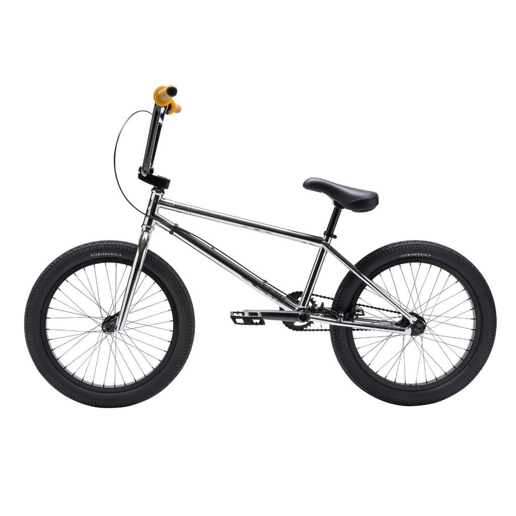 The Fit Bike Co Flow 20 Inch Bike features a chrome BMX dirt jump frame, black tires, saddle, and pedals, yellow handlebar grips, and is shown in profile against a white background.