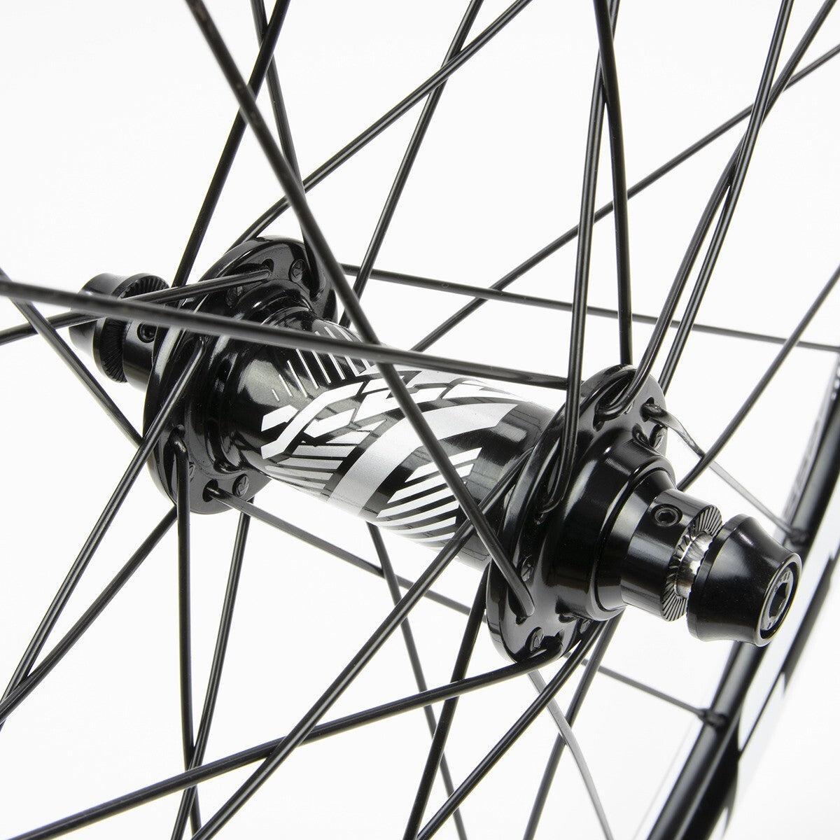 Close-up of the Excess XLC-2 20 x 1.3/8 Alloy Wheel Set 36H hub with black spokes and a patterned design, shown against a white background.