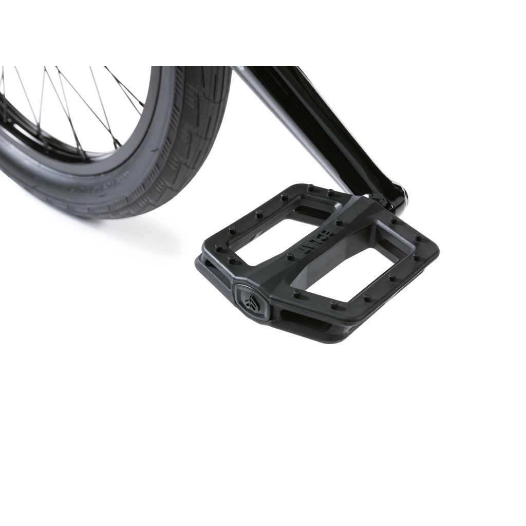 Close-up of a black, textured pedal and rear wheel on the Wethepeople Envy 20 Inch Bike—a BMX masterpiece. The distinct tire tread pattern ensures style and performance seamlessly unite.