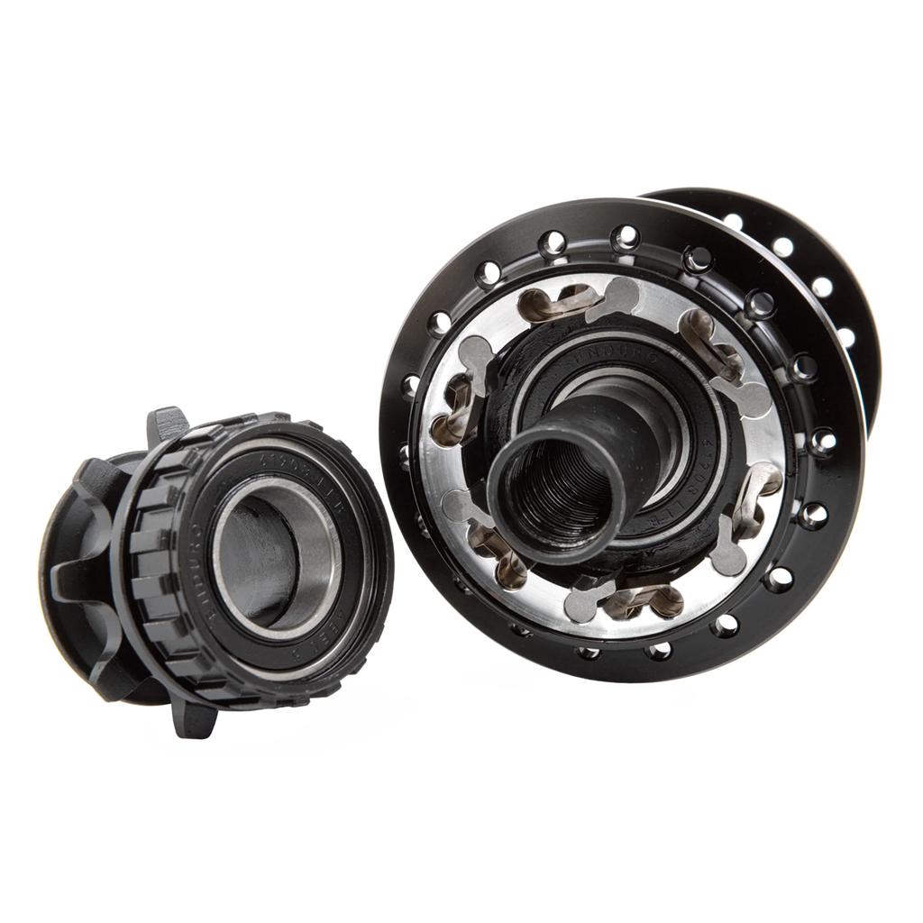 Close-up view of two black Odyssey Hexagram Rear Cassette Hub components with visible ball bearings and spoke holes, set against a white background. One features a switchable RHD/LHD hub design with 6-pawl engagement for enhanced performance and versatility.