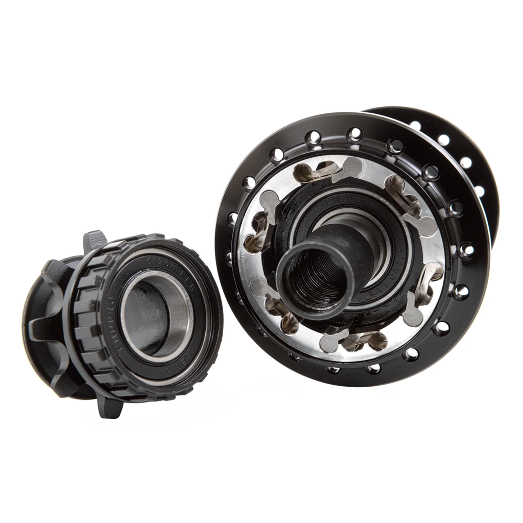 Close-up view of two black Odyssey Hexagram Rear Cassette Hub components with visible ball bearings and spoke holes, set against a white background. One features a switchable RHD/LHD hub design with 6-pawl engagement for enhanced performance and versatility.