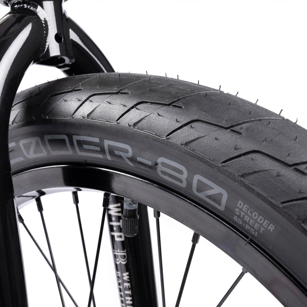 A close up of a black bicycle tire featuring the Wethepeople Battleship 20 Inch BMX Bike parts.