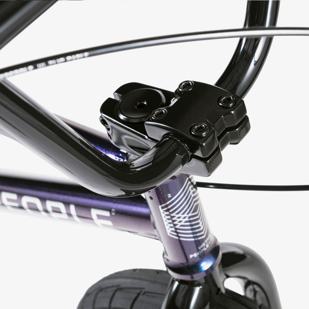 A close up of the handlebars of a purple Wethepeople CRS 20 Inch Bike.