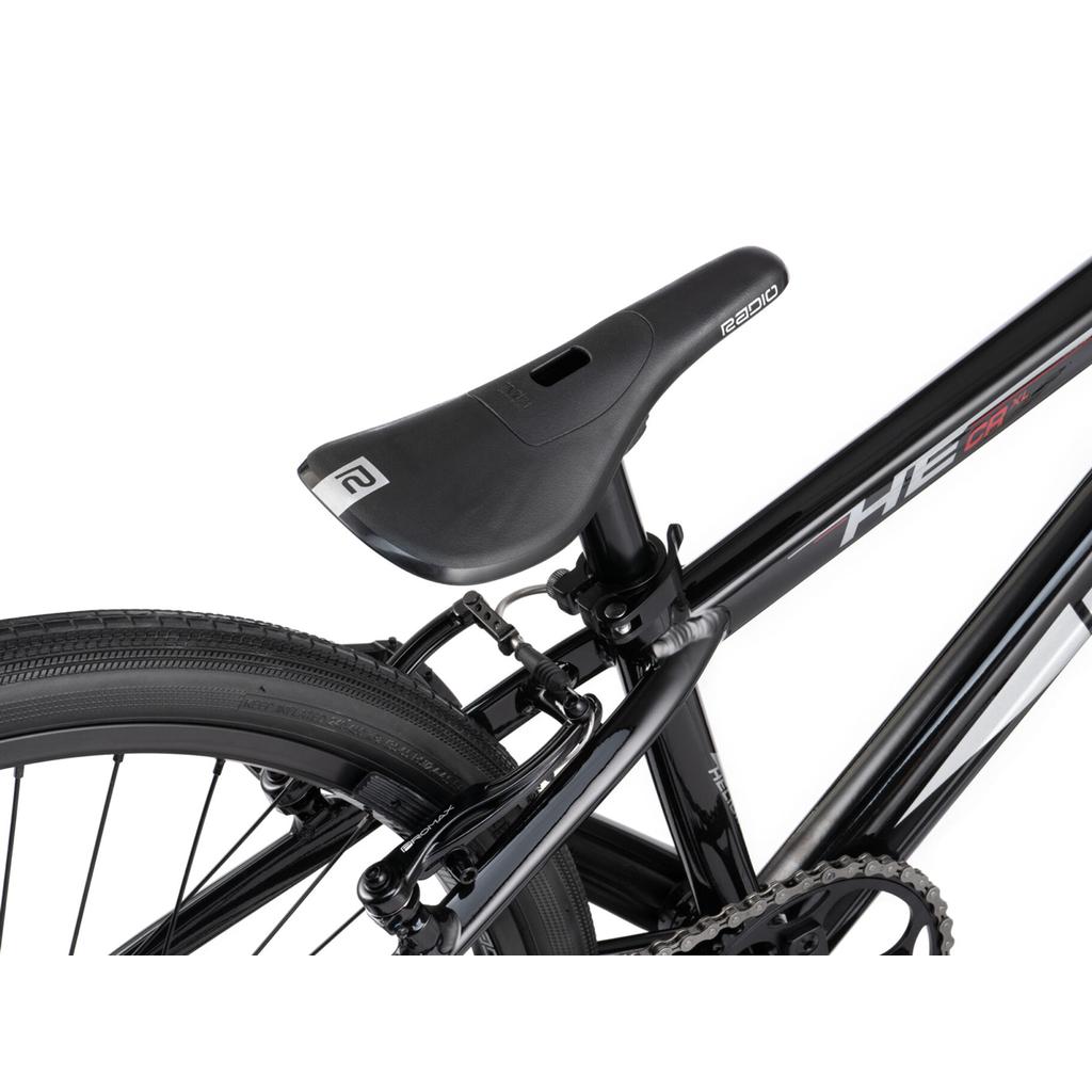 Close-up of a black bicycle seat, rear wheel, and part of the frame on a Radio Helium Pro 24 Inch Cruiser Bike, highlighting the seat post and tire tread details.