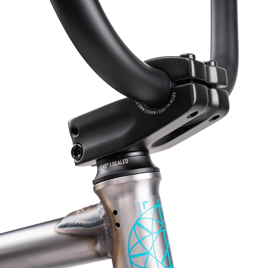 Close-up view of a Wethepeople Justice 20 Inch Bike's handlebars and stem, showcasing the front fork, head tube, and part of the bike's frame with a design on it.