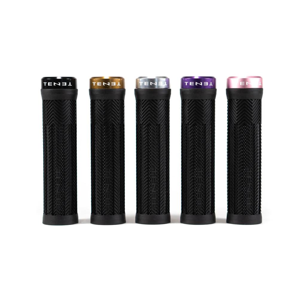 Five Tenet Components Icon Grips in black, each with a textured surface and a distinctively colored metal lock-on end cap in black, gold, silver, purple, and pink. These extra-soft rubber grips offer superior comfort and control for your mountain bike rides.
