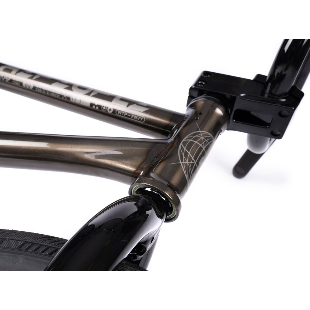 A close-up of the Wethepeople Envy 20 Inch Bike frame highlights its metallic finish and geometric design, complemented by black tires. This BMX masterpiece features Eclat Tibia Cranks for unmatched performance.