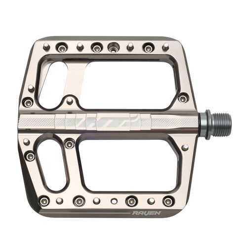 The HT Components ANS12 Raven Pedals are metallic flat mountain bike pedals with multiple grip pins, rectangular cutouts, and "RAVEN" engraved on the side, designed for excellent traction and durability.