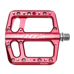 The HT Components ANS12 Raven Pedals feature a red aluminum body, large platform, multiple grip pins, and an axle for easy attachment. "RAVEN" is printed near the edge for a distinct look.