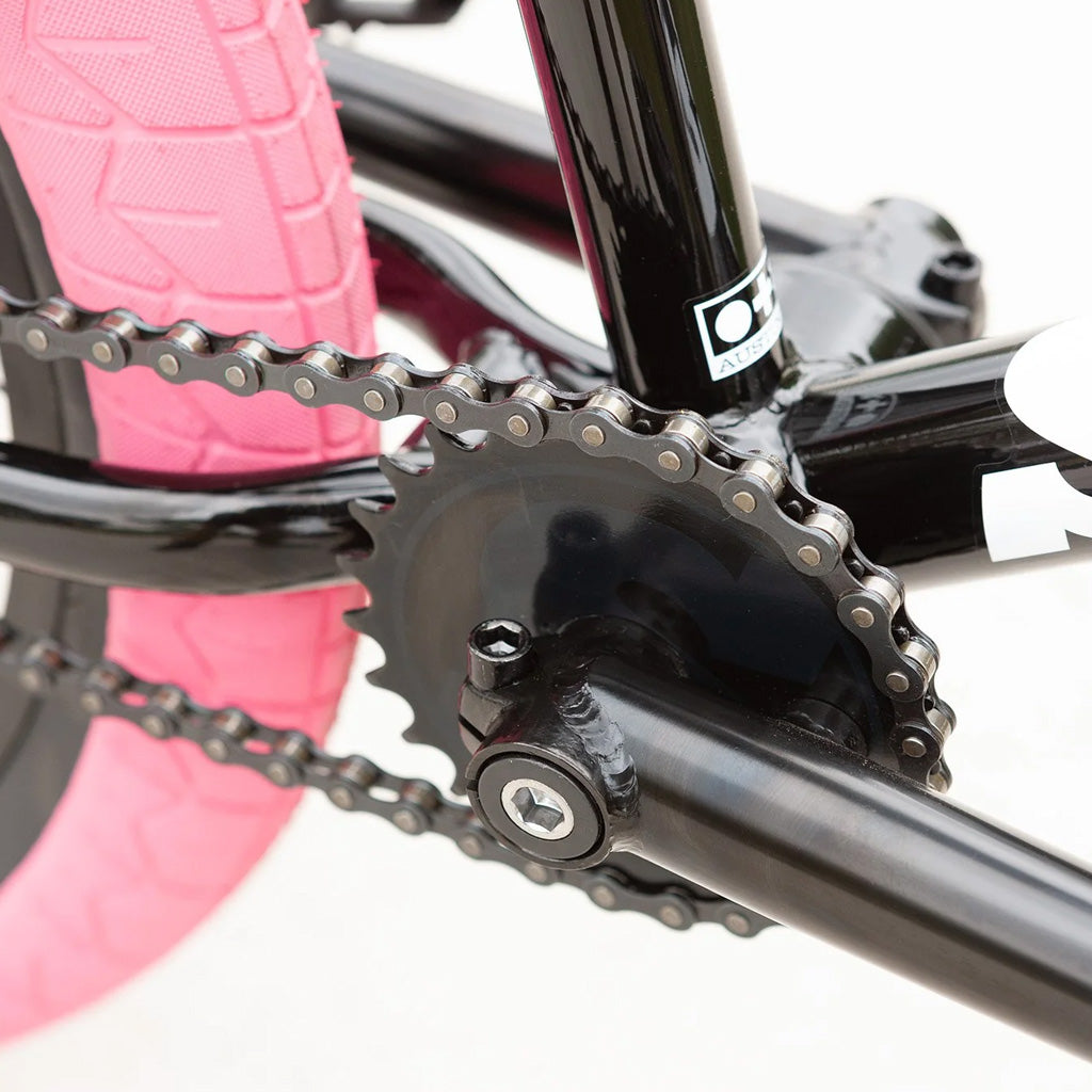 A close up of a Sunday Blueprint 20 inch Bike with a pink chain.