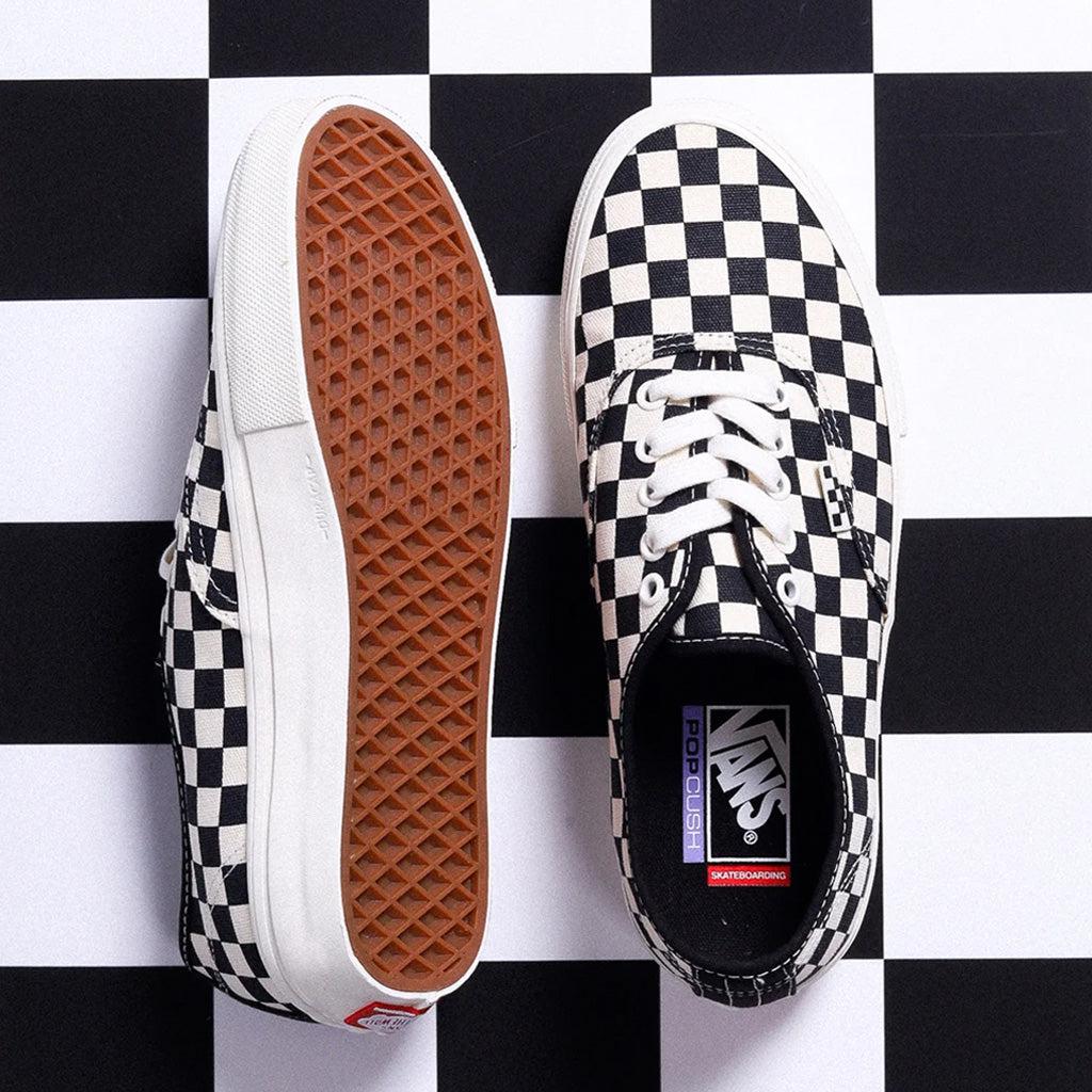 A pair of black and white checkered Vans Pro Skate Authentic Checkerboard/Marshmallow Shoes on top of a checkered board, showcasing their comfort and durability.