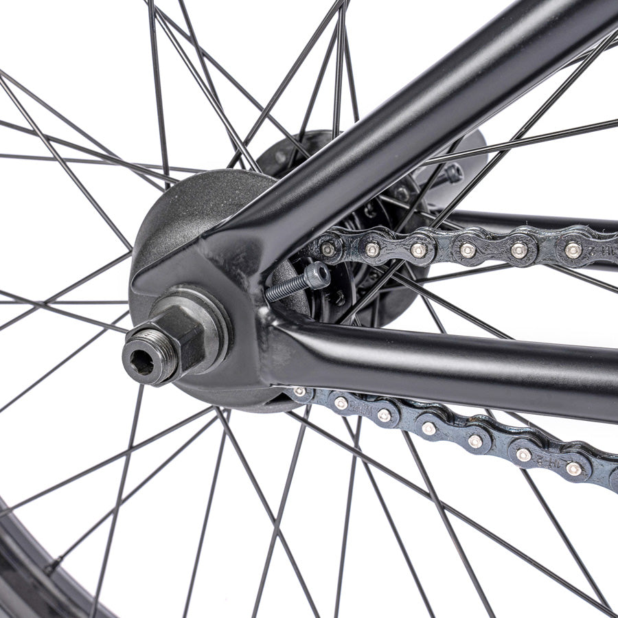 A close up of a black bike wheel with chains featuring the Wethepeople Trust 20 Inch Cassette Bike.