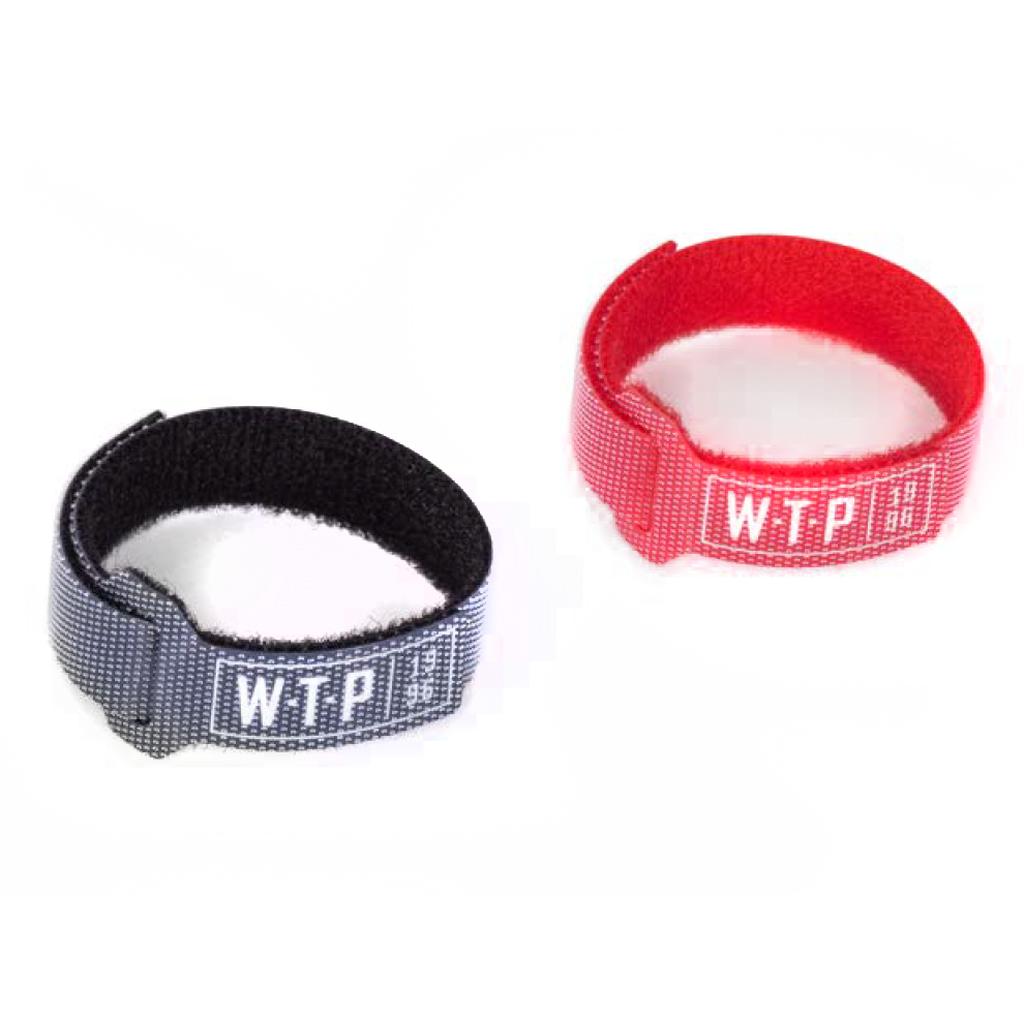 The Wethepeople Brake Cable Velcro Holder includes two nylon hook-and-loop straps—one black, one red—each labeled "WTP," ideal for cable management. Both Velcro holders are shown on a white background.